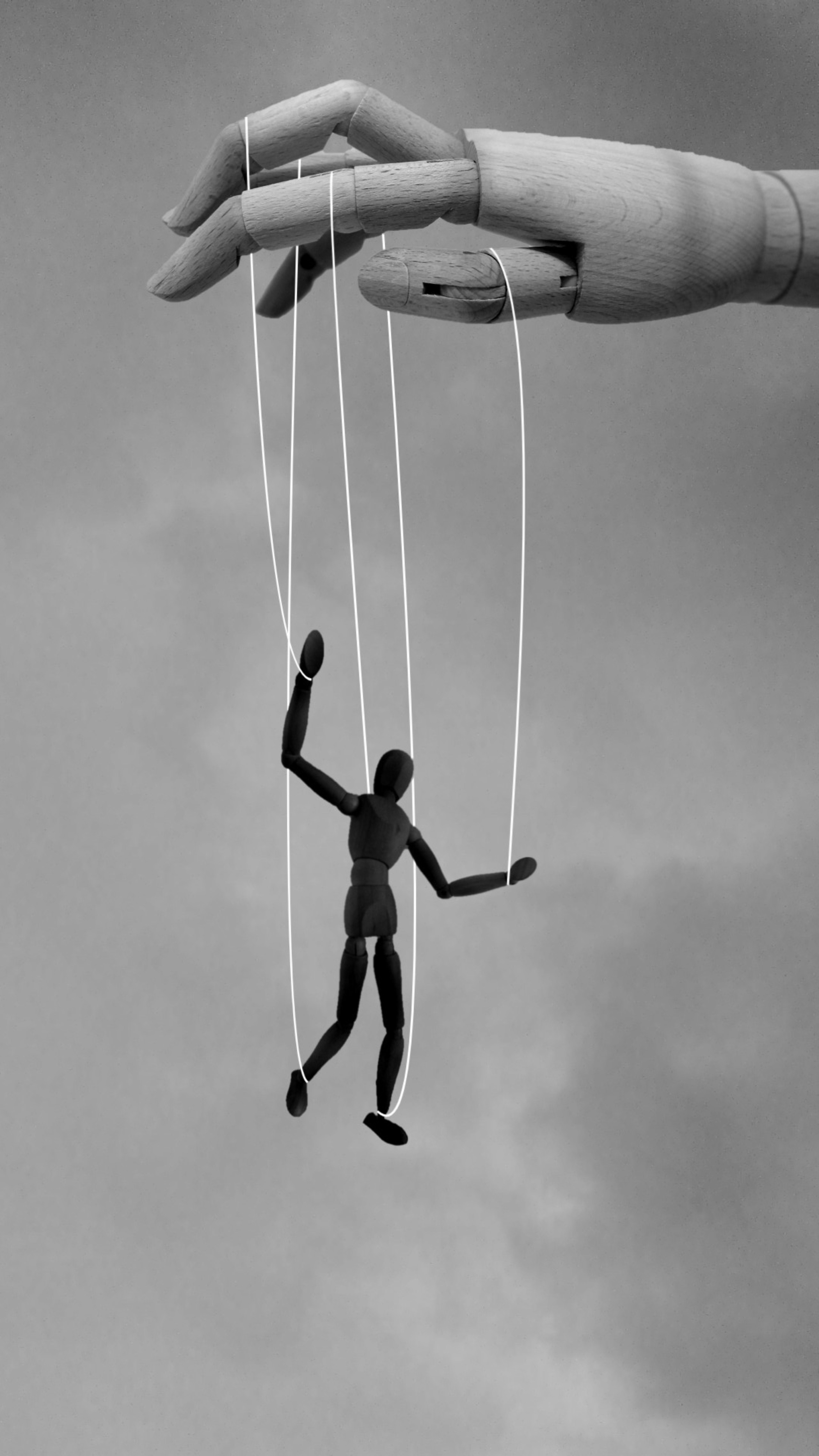 Wooden marionette controlled by a larger wooden hand, illustrating power and control.