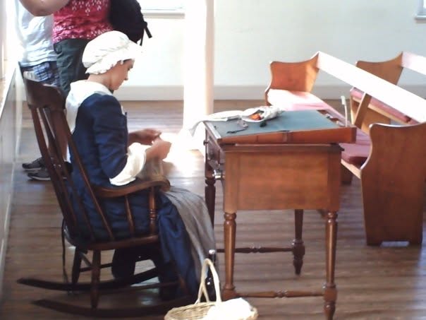 Historical reenactor seated at a writing desk in period clothing